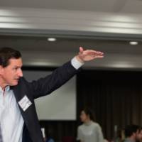 Steve Goreham gestures with his hand while engaging in discussion with several attendees.